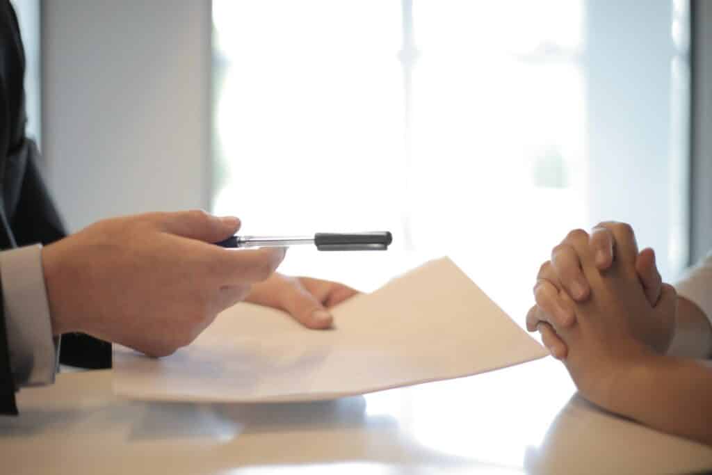 How a negative interview experience will impact your hiring process in 2023 1 A person handing a pen and paper to another in an interview skill test