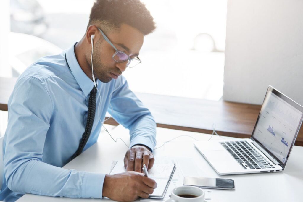 How to Prevent Cheating in Online Skills Assessments (and Why Fair AI Matters) 4 Man using a laptop and taking notes to prevent cheating in online skills assessments